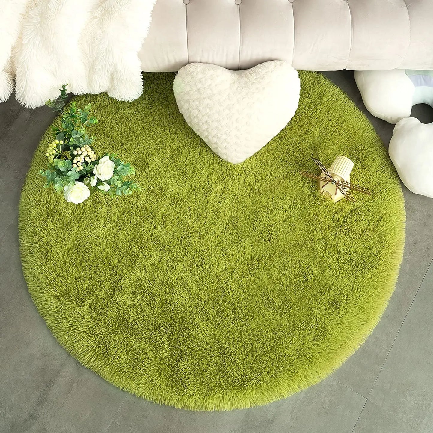 Boule de Noël et train miniature posés sur un tapis vert poil long, encart macro sur la fibre