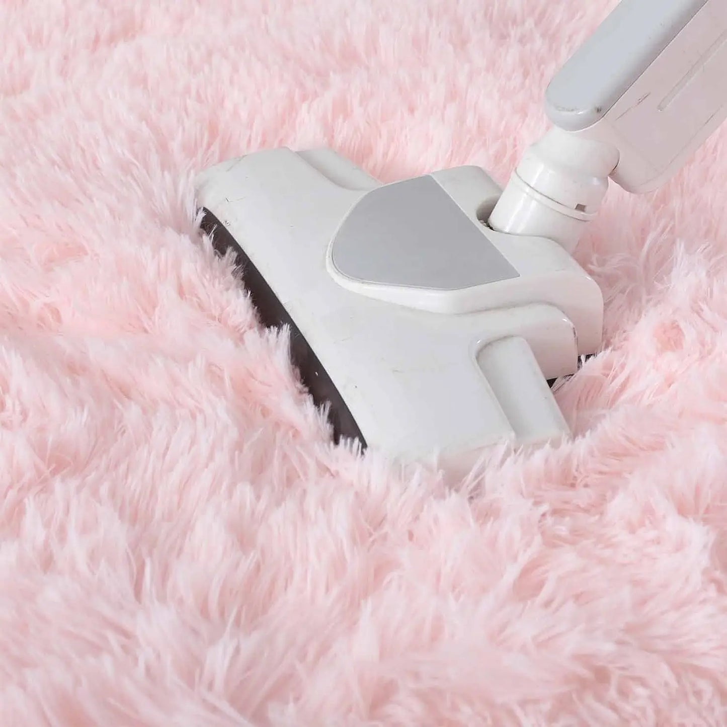 Aspirateur passé sur le tapis rond rose poil long, démonstration entretien
