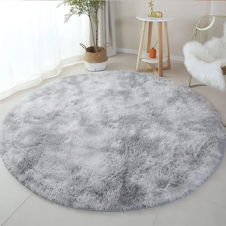 Tapis rond gris chiné dans un coin lecture avec fauteuil blanc en fausse fourrure et plante en panier osier