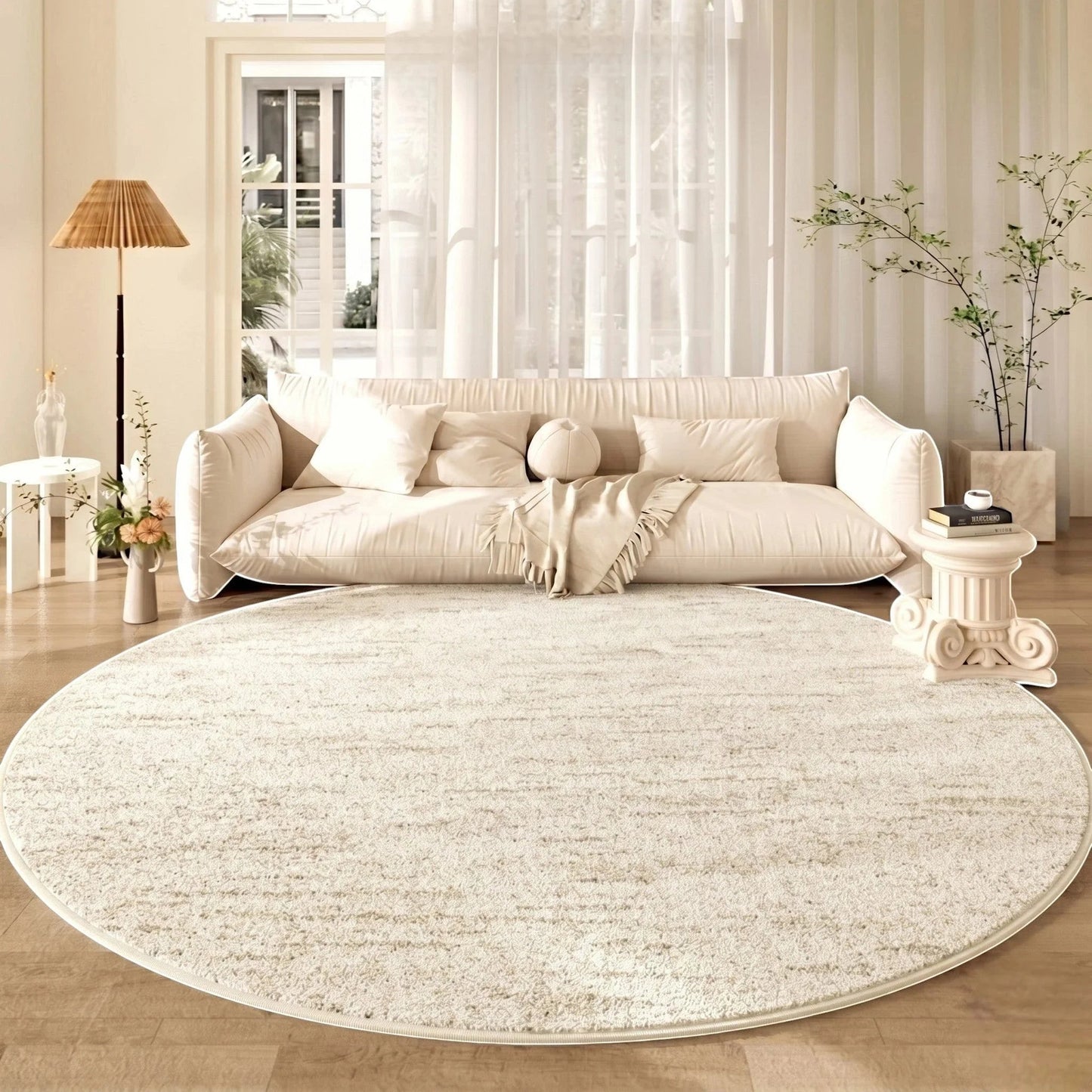 Tapis rond beige cercles concentriques sous un canapé crème nuage devant une baie vitrée en lin et des plantes