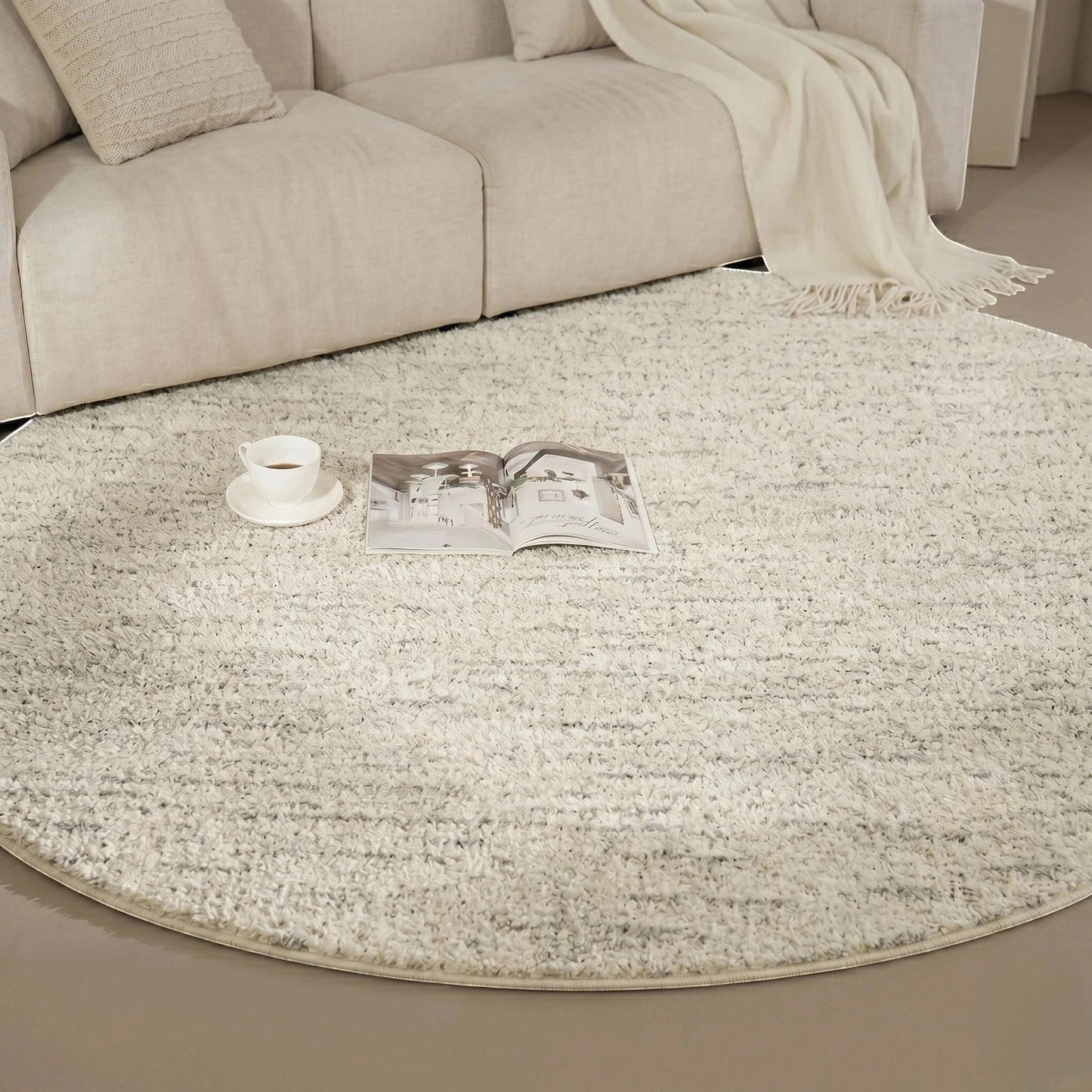 Détail rapproché du tapis rond beige cercles concentriques avec une tasse et un livre ouvert dans un coin lecture