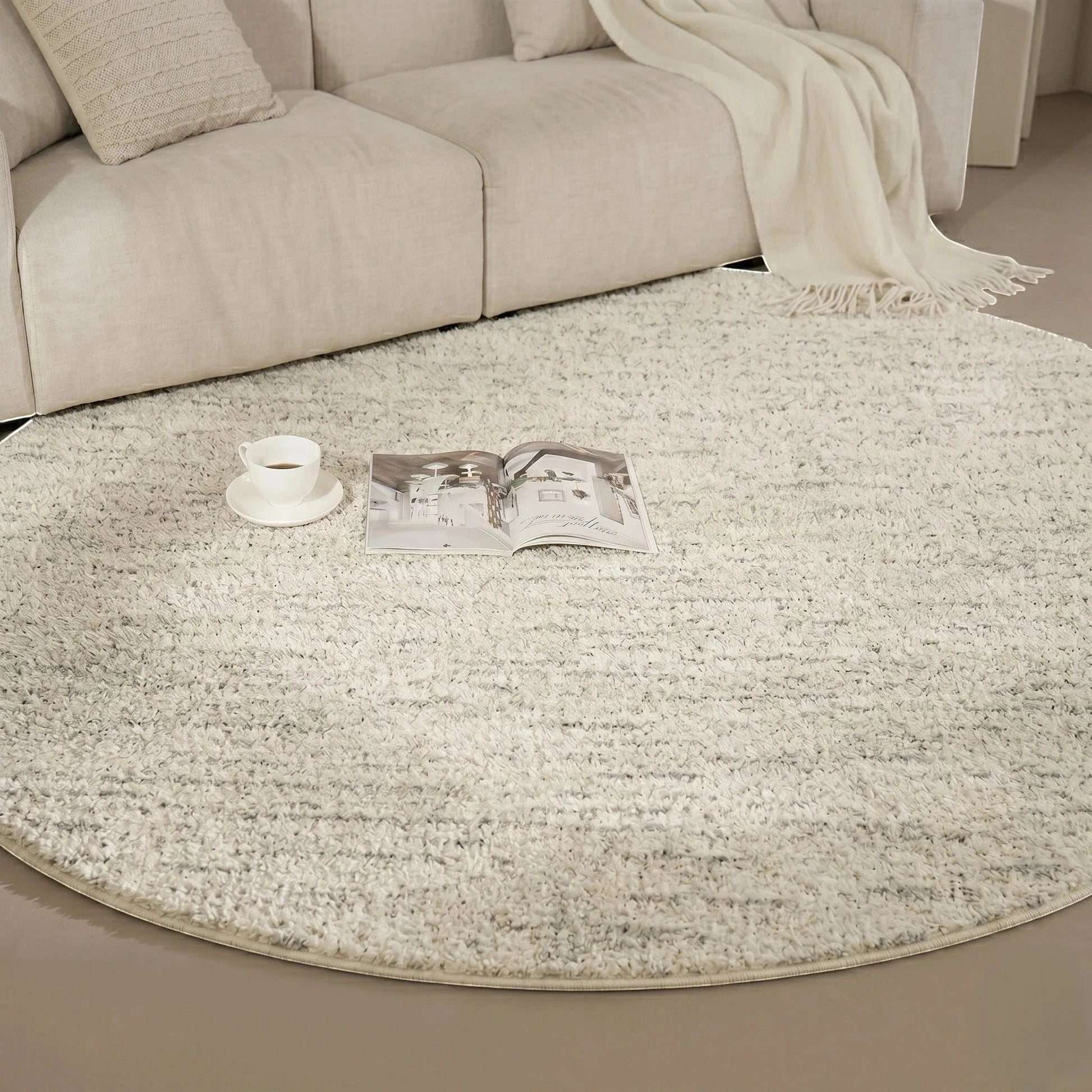 Détail rapproché du tapis rond beige cercles concentriques avec une tasse et un livre ouvert dans un coin lecture
