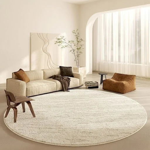 Tapis rond beige cercles concentriques dans un grand salon lumineux avec canapé crème, fauteuil pouf caramel et chaise en bois courbé