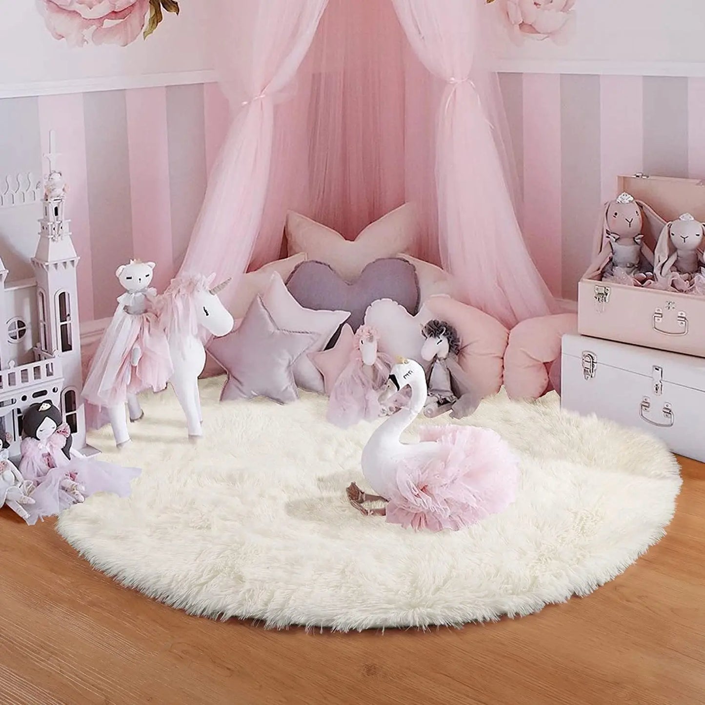 Tapis rond blanc au pied d'un lit-baldaquin rose, peluches licorne et cygne en décor