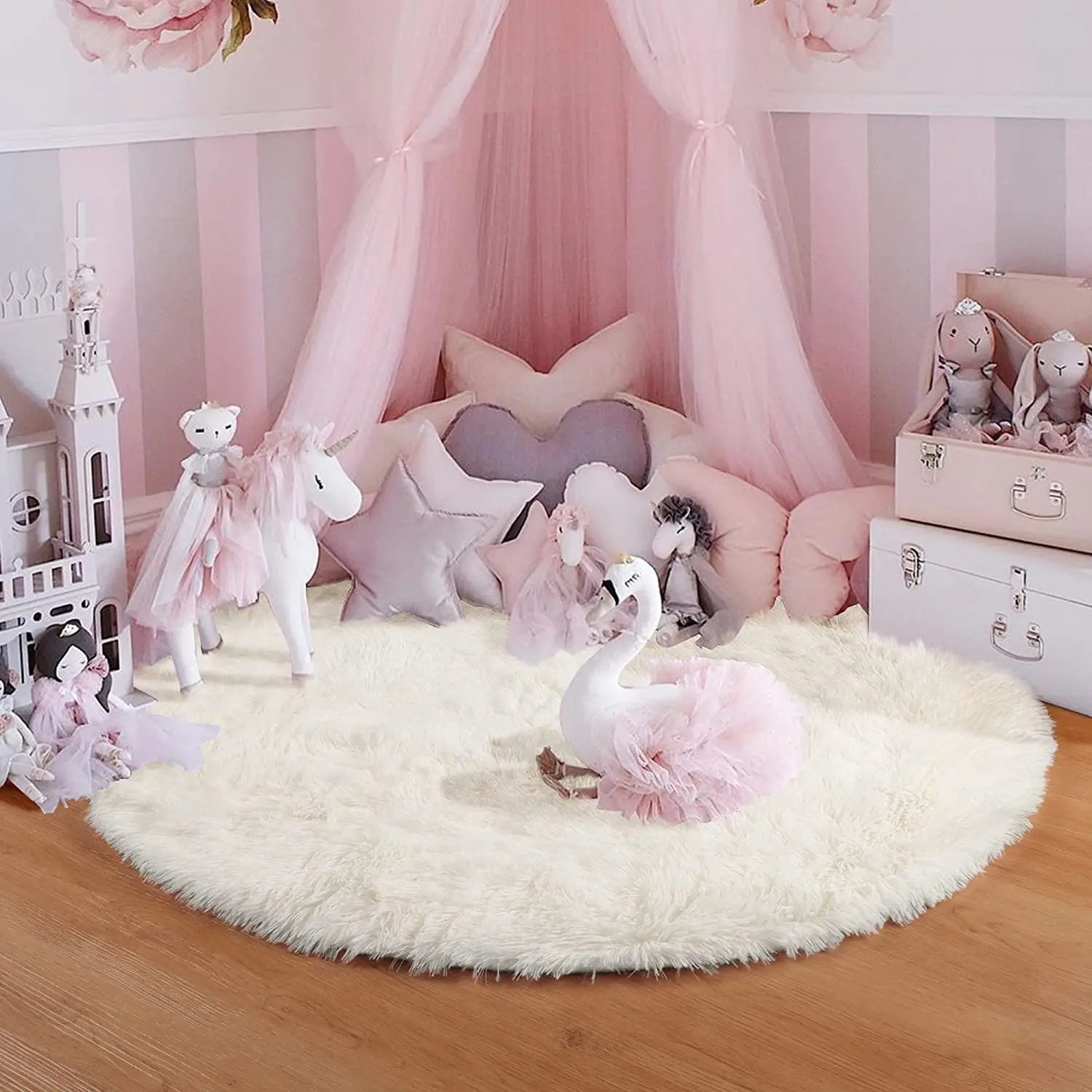 Tapis rond blanc au pied d'un lit-baldaquin rose, peluches licorne et cygne en décor