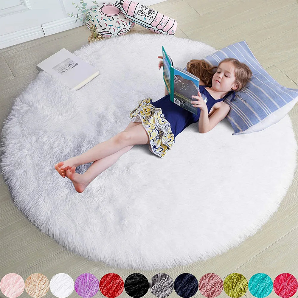 Petite fille lisant un livre, allongée sur un tapis rond blanc poil long, coussin rayé bleu en appui-tête