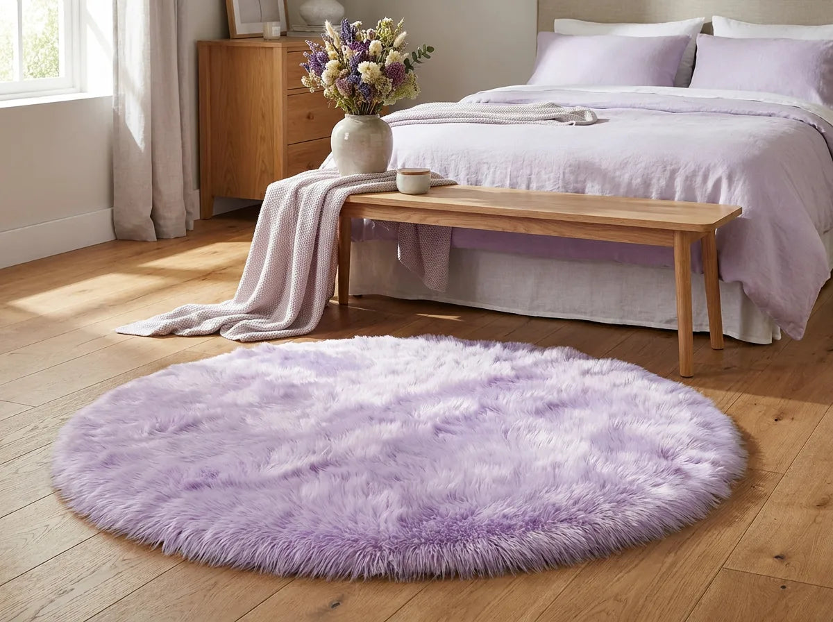 Tapis rond chambre moelleux mauve au pied du lit, devant un banc en bois clair