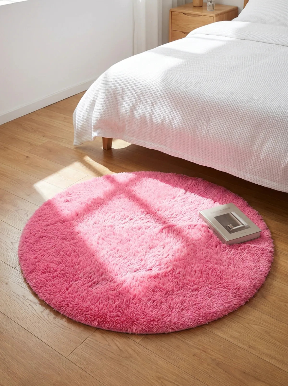 Tapis rond chambre moelleux rose en descente de lit dans une chambre aux murs blancs