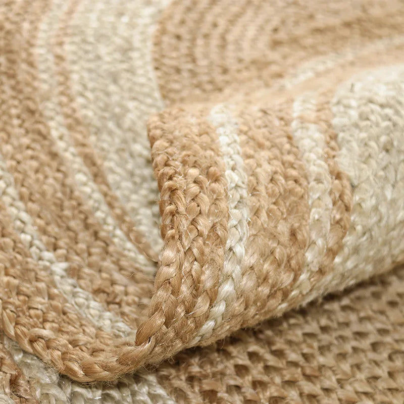Bord replié du tapis rond en jute tressé anneaux écru, gros plan sur les bandes contrastées