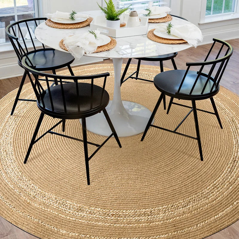 Tapis rond en jute naturel sous une table à manger en marbre avec chaises noires