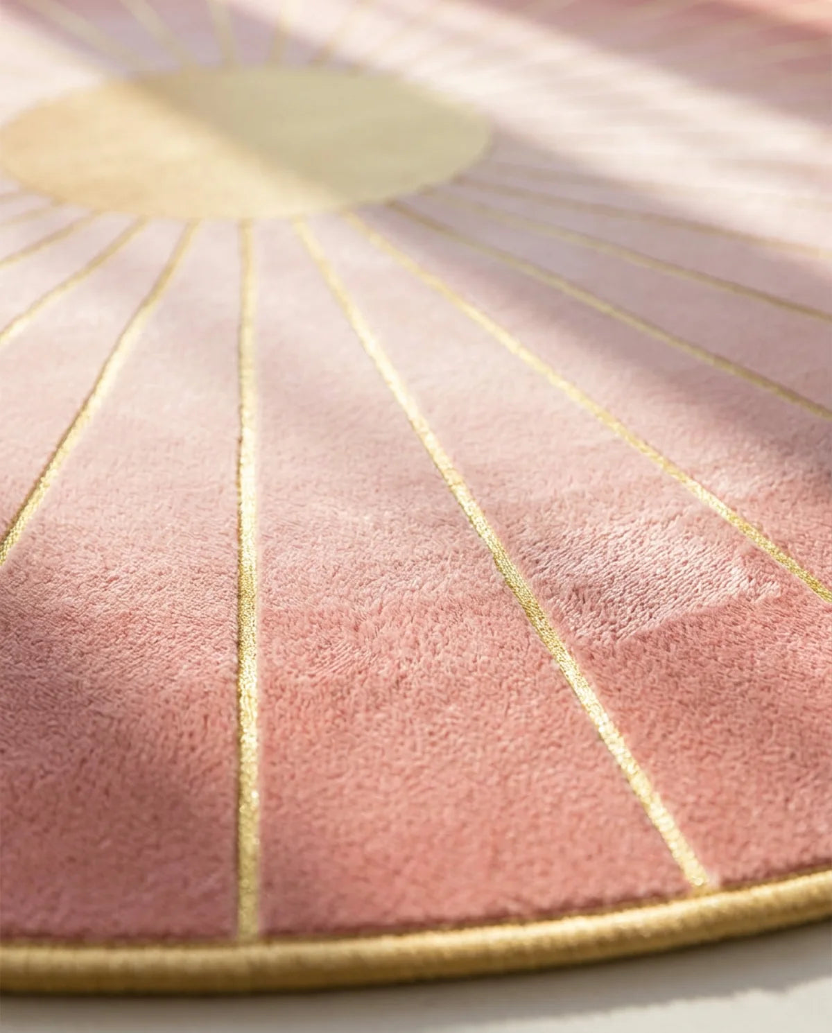 Détail des rayons roses et traits dorés du tapis rond lavable