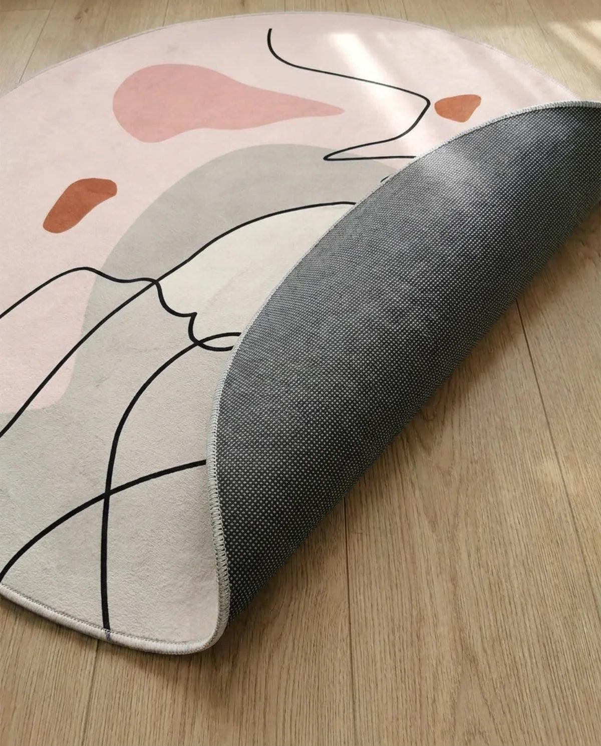 Profil fin et sous-face antidérapante du tapis rond lavable rose tracé organique