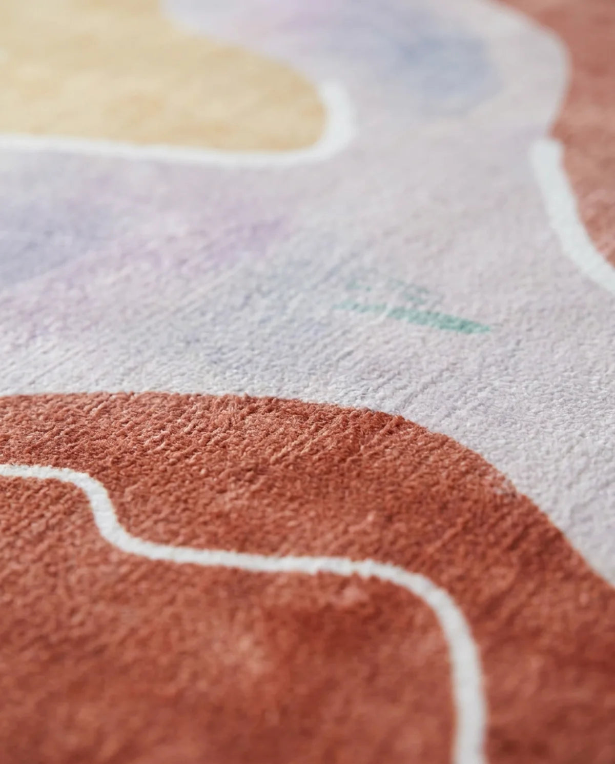 Détail du velours ras imprimé du tapis rond lavable terracotta aquarelle