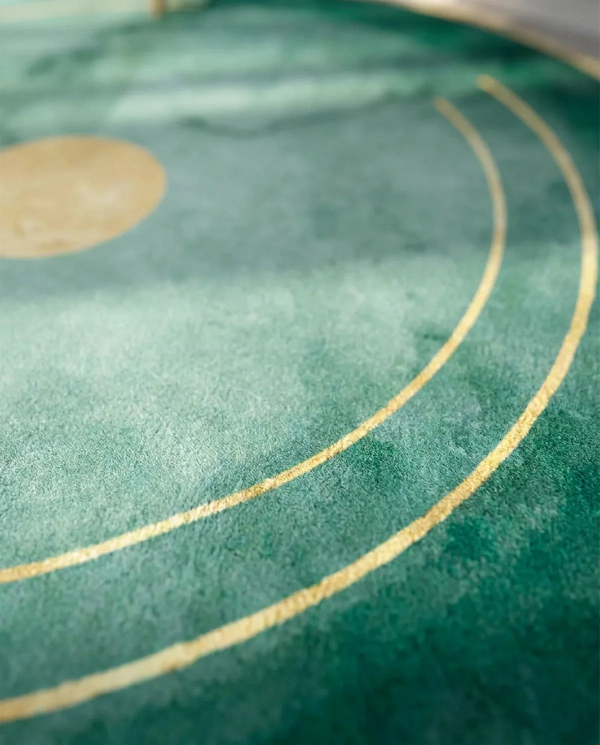Détail du cercle doré sur le dégradé émeraude du tapis rond lavable