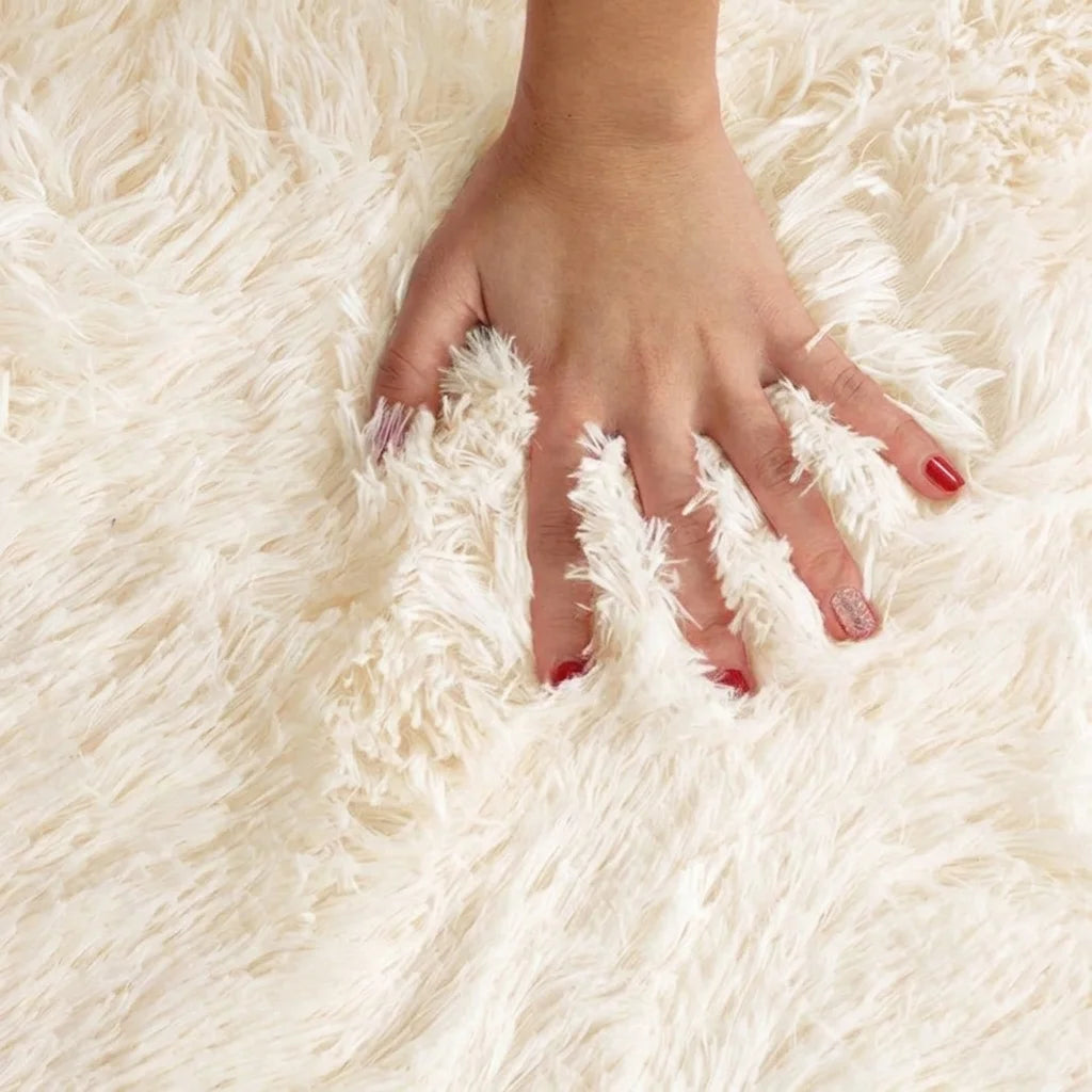 Macro de la peluche du tapis rond salle de bain moelleux blanc crème, main posée sur les fibres longues
