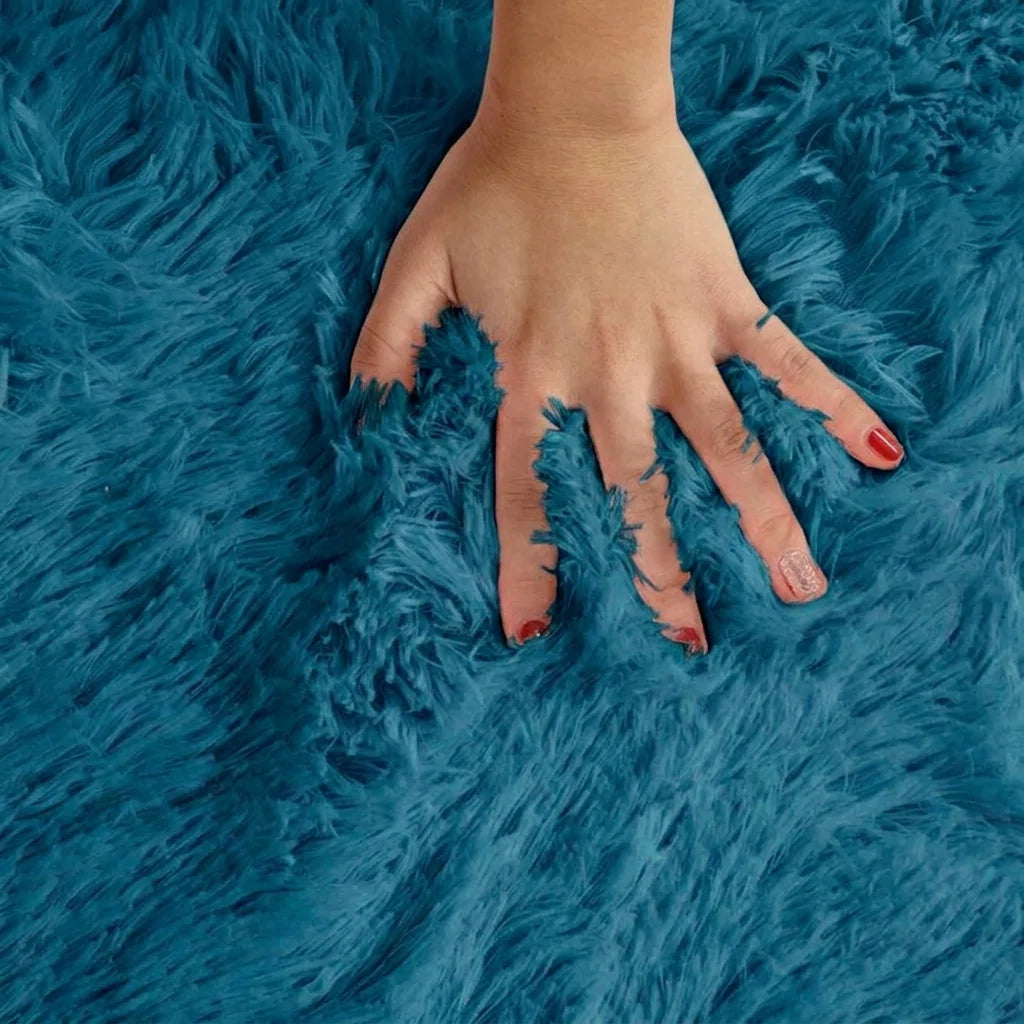 Macro de la peluche du tapis rond salle de bain moelleux bleu canard, main posée sur les fibres longues