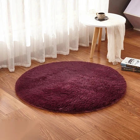 Photo originale du tapis rond moelleux rouge bordeaux dans un salon, sur parquet bois clair