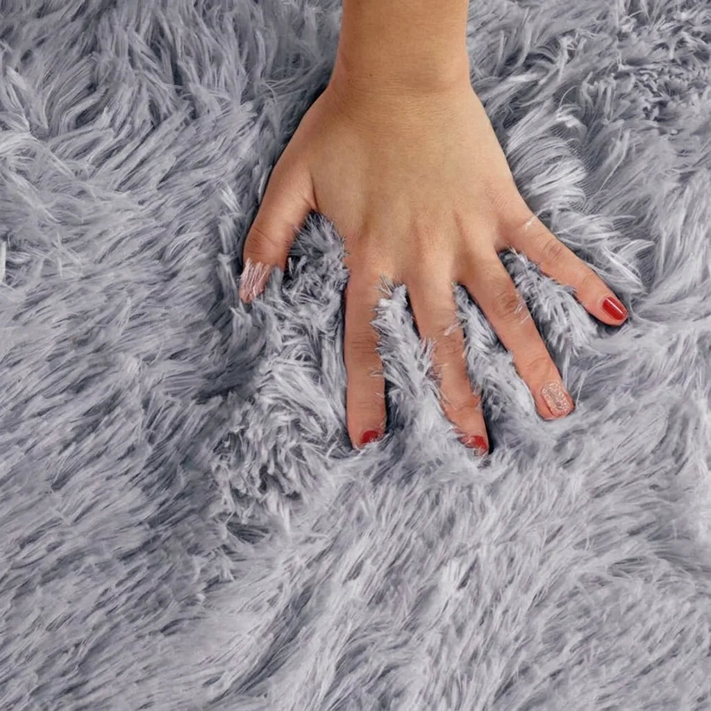 Macro de la peluche du tapis rond salle de bain moelleux gris perle, main posée sur les fibres longues
