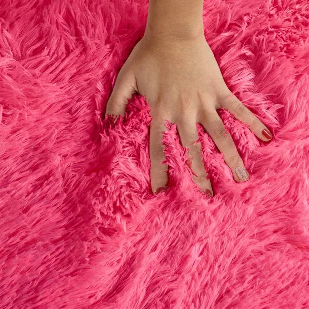 Macro de la peluche du tapis rond salle de bain moelleux rose, main posée sur les fibres longues