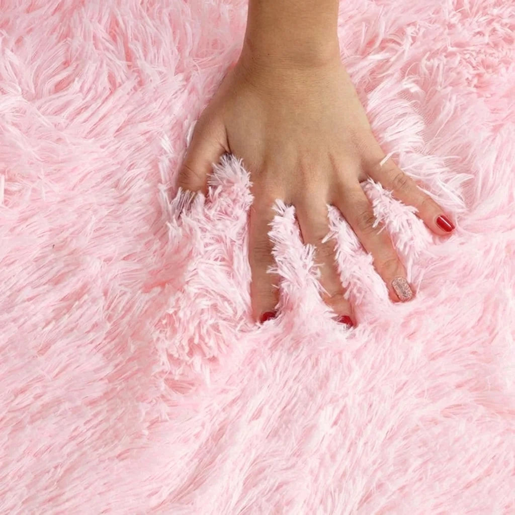 Macro de la peluche du tapis rond salle de bain moelleux rose pâle, main posée sur les fibres longues