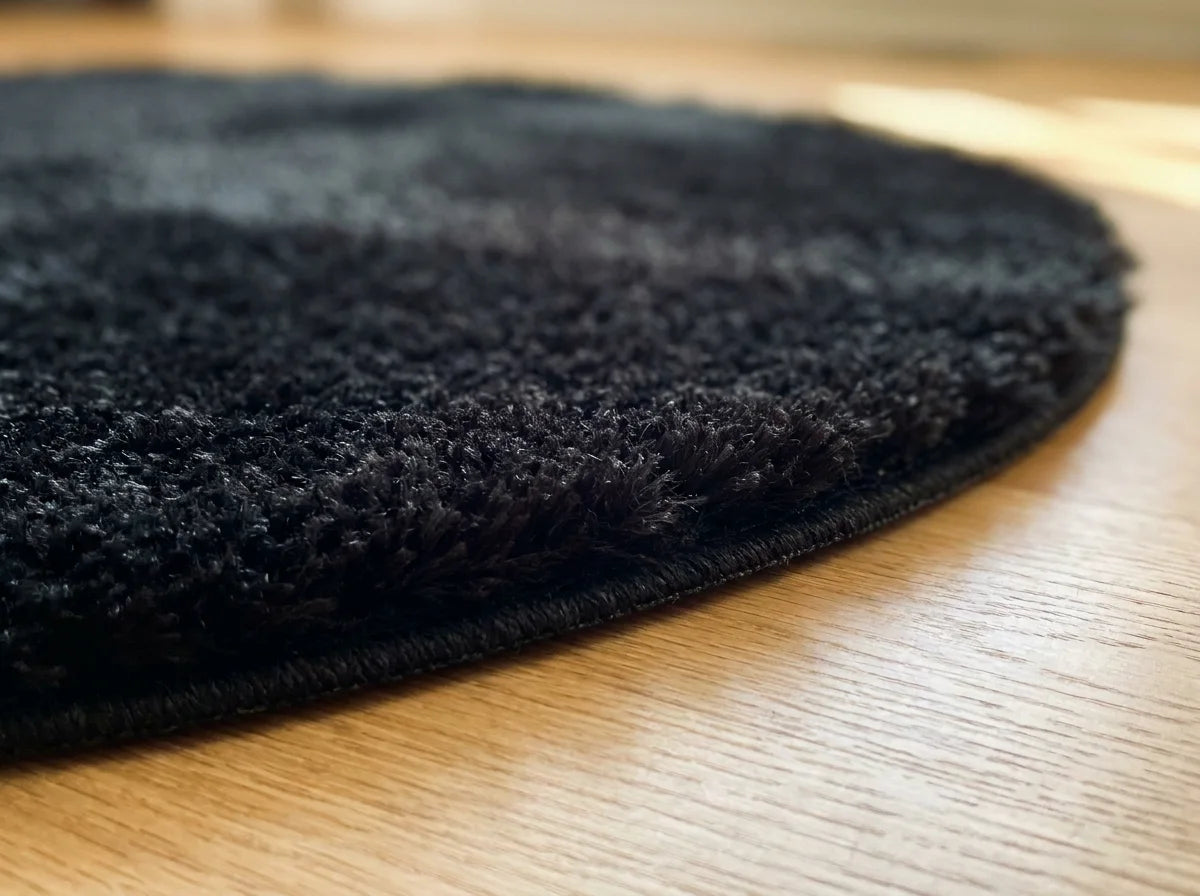Tranche du tapis rond chambre moelleux noir montrant l'épaisseur du tissage