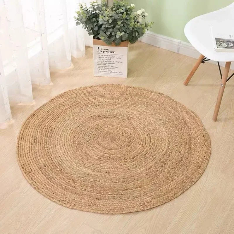 Tapis rond rotin nattes épaisses seul sur parquet clair avec plante en sac papier en arrière-plan