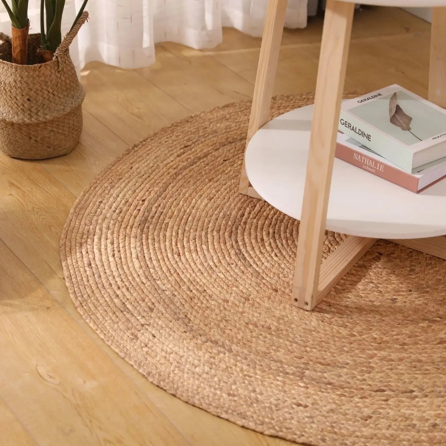 Détail du tapis rond rotin spirale tressée sous une table basse avec livres et plante en panier