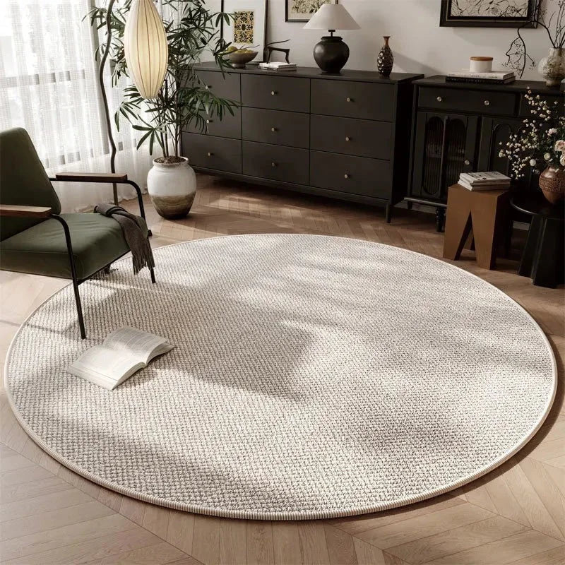 Tapis rond Wilton tissage plat écru dans un salon japandi avec commode foncée et fauteuil vert