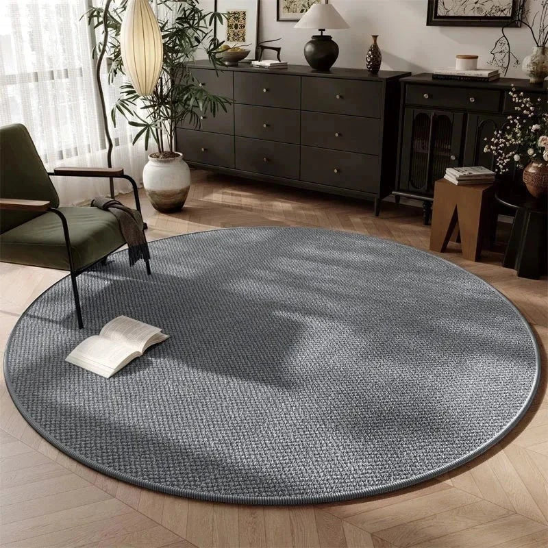Tapis rond Wilton tissage plat gris ardoise dans un salon contemporain avec commode noire et fauteuil bouclé vert